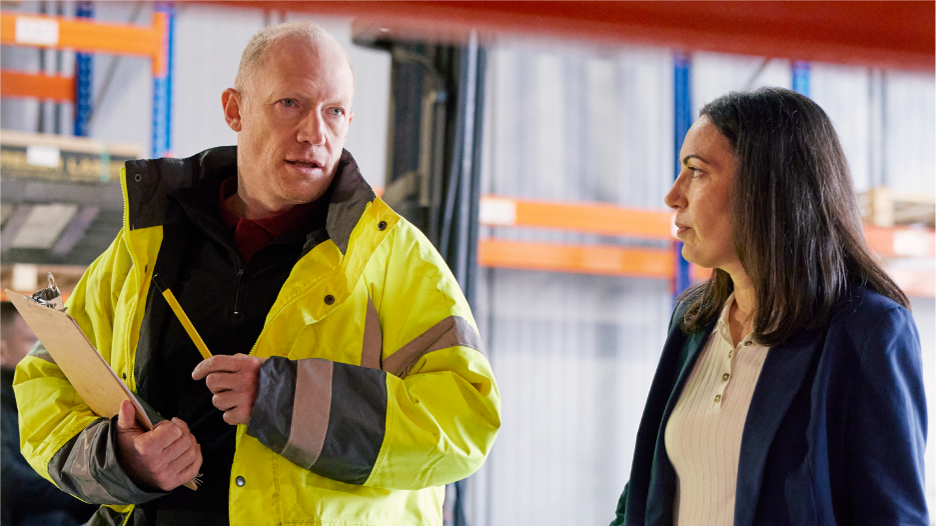 Warehouse worker talking to a female professional