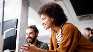 Male and female coworkers smiling at computer screen 