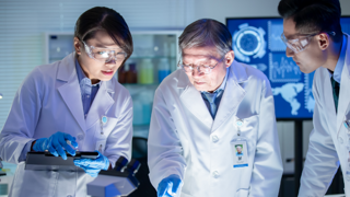 three scientist looking at lab table 