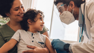 Doctor examining child who is held on mothers lap