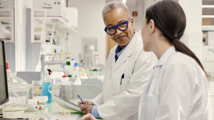 Two female scientists in lab smiling and working