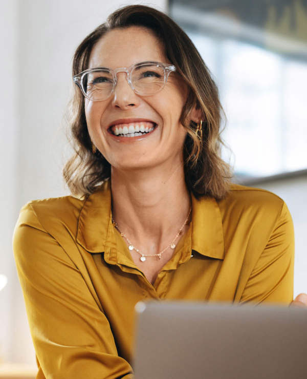 Woman with glassed smiling behind computer