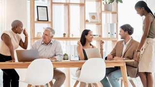 Five coworkers sitting around a desk