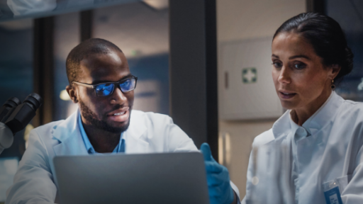 two biotech researchers discussing what is on a laptop screen
