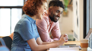 Photo of two people sitting at a desk looking at a laptop