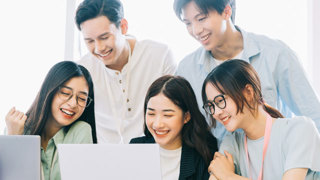 5 individuals smiling around a computer