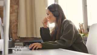 Woman working from home with headphones on at computer