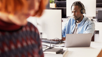 Photo of someone working at a desk with headphones