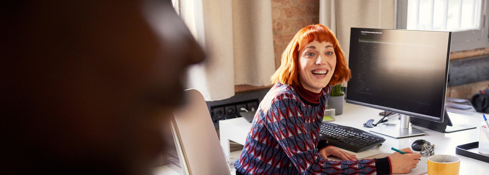 Person sitting at computer turned looking at camera