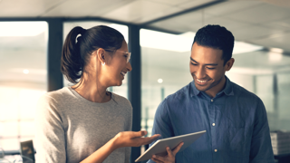 Photo of two people standing holding a tablet