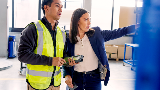 Two people in warehouse pointing off to the side