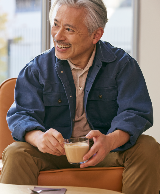 Man sitting in chair holding coffee and smiling