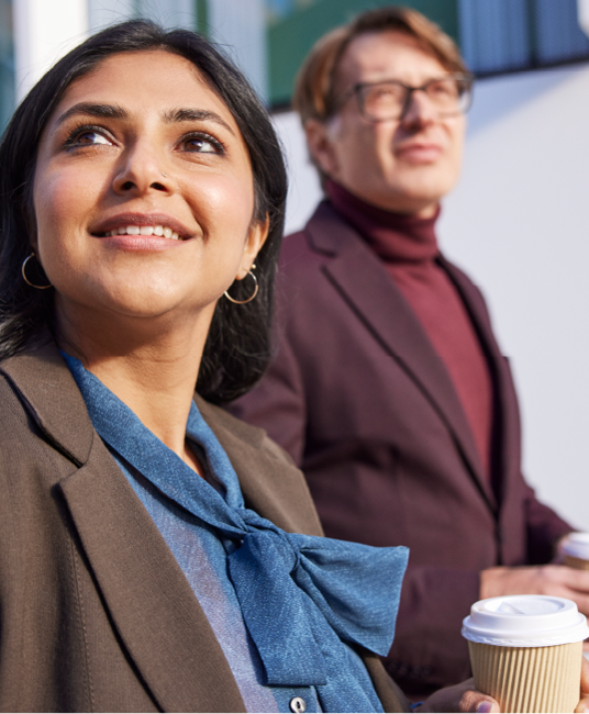 Two professional people walking while holding coffees