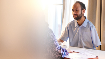 Photo of person at desk interviewing another person