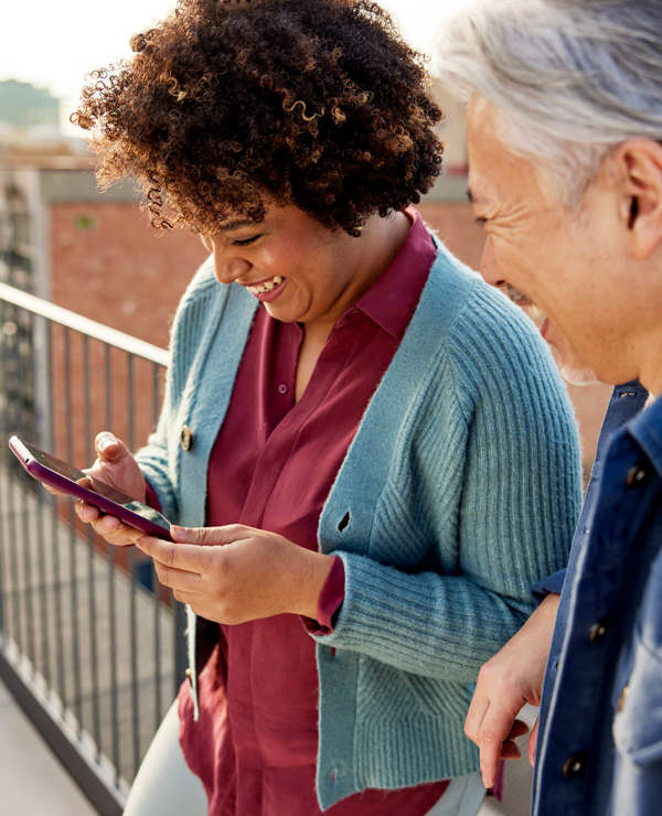 Woman smiling looking at phone with colleague by her side