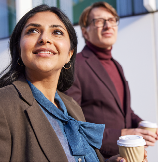 two professional co-workers walking holding coffees