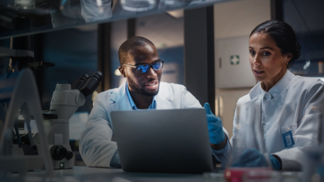 two biotech researchers discussing what is on a laptop screen