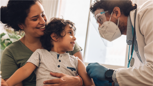 A medical professional attending to a child patient that is being held in a mothers lap 